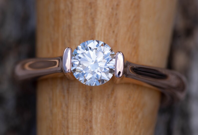 May include: A silver ring with a large, clear, round diamond set in the center.