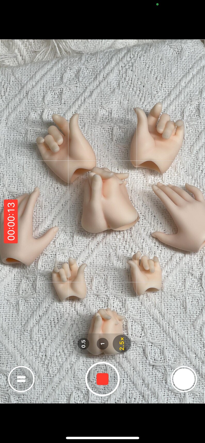 May include: A collection of articulated doll hands in various poses, made of a pale, flesh-toned material. The hands are arranged on a white, textured surface, with a timer overlay in the upper left corner.