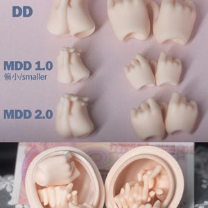 May include: A collection of pale pink doll hands in various poses and sizes, labeled DD, MDD 1.0, and MDD 2.0. The image includes text that reads "Hand A" and "Hand B". The bottom of the image shows two doll heads with hands inside. The text "SemiWhite" and "Flesh" is also visible.