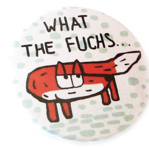 Könnte beinhalten: Ein weißer Knopf mit einer roten Fuchs-Karikatur und dem Text "WHAT THE FUCHS..." auf weißem Hintergrund mit grünen Punkten.