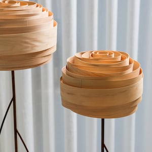 May include: Two wooden lamps with a unique, layered, rose-like design. The lamps are on tall, thin, black metal stands.