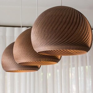 May include: Three brown wooden pendant lights with a ribbed design hang from the ceiling.