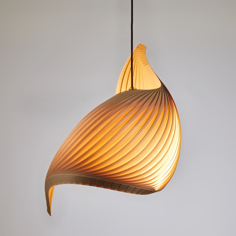 K&ouml;nnte beinhalten: Eine Holz-Pendelleuchte mit einem einzigartigen, geschwungenen und spiralf&ouml;rmigen Design. Die Leuchte besteht aus d&uuml;nnen Holzlamellen, die ein warmes, nat&uuml;rliches Aussehen erzeugen.