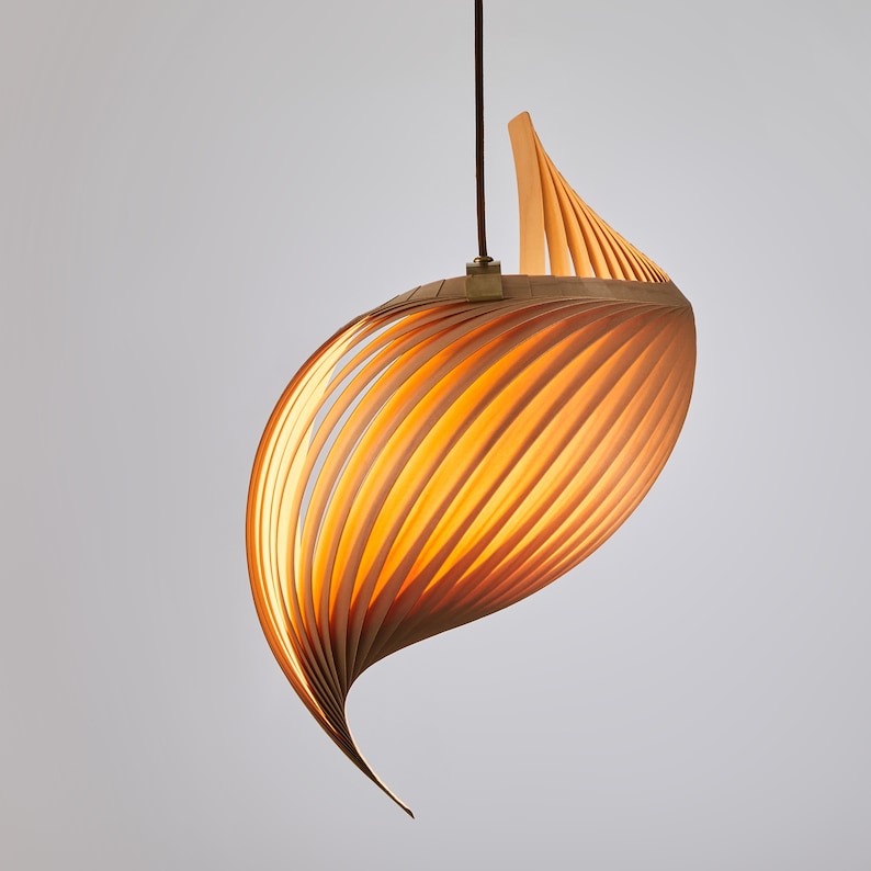 K&ouml;nnte beinhalten: Eine Holz-Pendelleuchte mit einem einzigartigen Spiraldesign. Die Leuchte besteht aus d&uuml;nnen Holzstreifen, die gebogen und &uuml;bereinander gelegt sind, um eine flie&szlig;ende, organische Form zu schaffen.