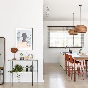 May include: A modern kitchen and dining area with white walls, a large window with blinds, a wooden dining table with six red chairs, and a black and white art print on the wall.