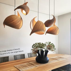 Op de afbeelding: Vijf houten hanglampen hangen boven een houten tafel met een vaas met bloemen in het midden. De lampen zijn spiraalvormig en hebben een natuurlijke houten afwerking. De afbeelding toont 5 armaturen. De prijs is voor één enkele armatuur.