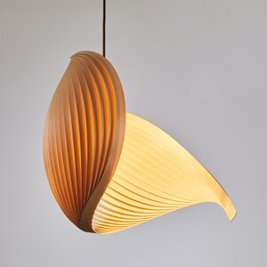 K&ouml;nnte beinhalten: Eine Holz-Pendelleuchte mit einem einzigartigen, geschwungenen Design. Die Leuchte besteht aus d&uuml;nnen, &uuml;berlappenden Holzlamellen, die ein warmes, nat&uuml;rliches Aussehen erzeugen.