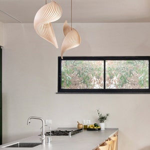 K&ouml;nnte beinhalten: Eine moderne K&uuml;che mit einer wei&szlig;en Arbeitsplatte und Holzschr&auml;nken. Es gibt vier Holzbarhocker und einen Wasserhahn aus Edelstahl. Die K&uuml;che hat ein gro&szlig;es Fenster mit Blick auf B&auml;ume und eine einzigartige Holzleuchte, die von der Decke h&auml;ngt.