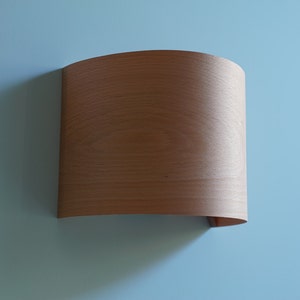 May include: A curved piece of wood veneer with a light brown color and a smooth surface.