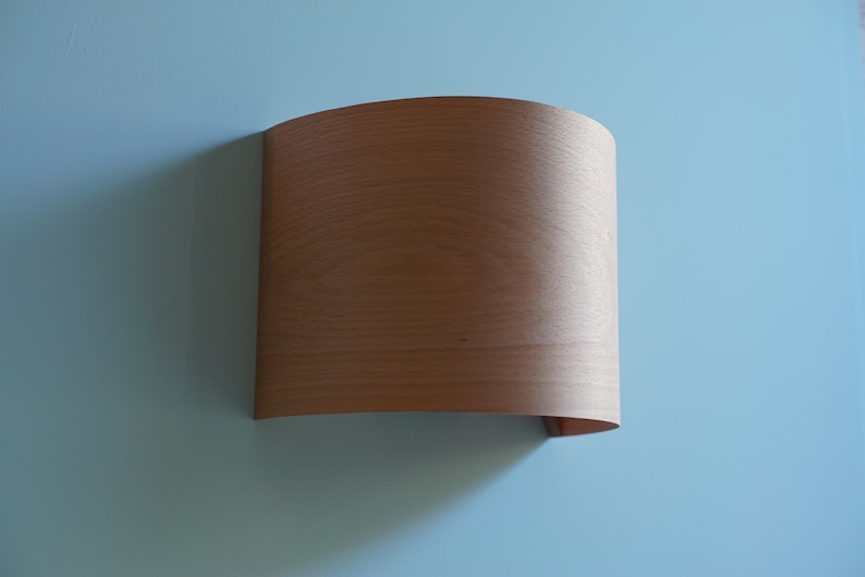 May include: A curved piece of wood veneer with a light brown color and a smooth surface.