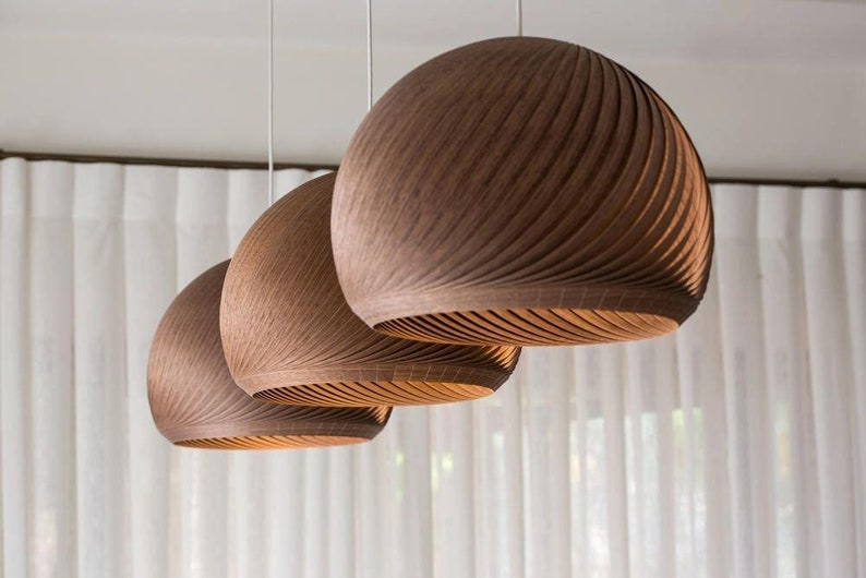 May include: Three brown wooden pendant lights with a ribbed design hang from the ceiling.