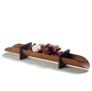 Puede incluir: Un plato de servir de madera con extremos negros, lleno de cebollas rojas y dientes de ajo.