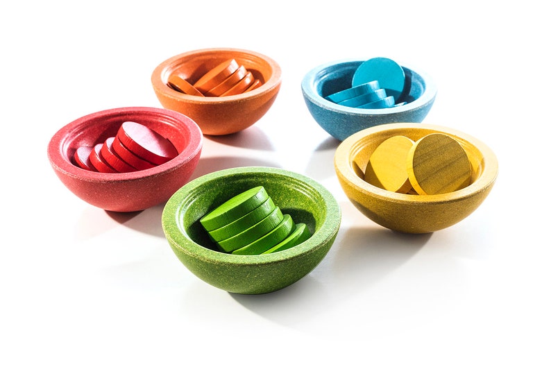 Peut inclure: Cinq bols en bois, chacun contenant une pile de disques en bois color&eacute;s. Les bols sont dans des tons d'orange, rouge, bleu, jaune et vert.