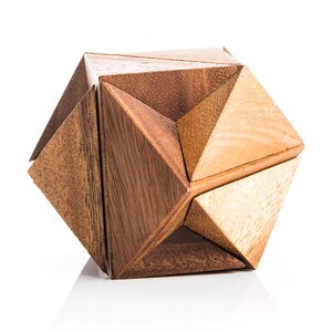 May include: A wooden puzzle in the shape of a geometric star. The puzzle is made of multiple pieces that fit together to form the star shape. The puzzle is made of light and dark brown wood.