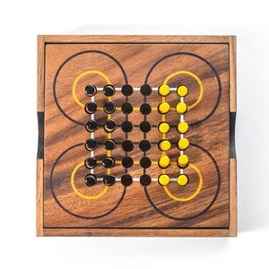 May include: A wooden game board with black and yellow pegs. The board has a circular pattern with concentric circles.