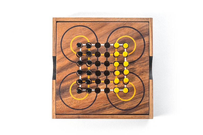May include: A wooden game board with black and yellow pegs. The board has a circular pattern with concentric circles.
