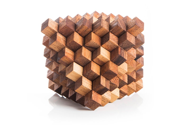 May include: A wooden puzzle cube made of many small, interlocking pieces. The cube is made of light and dark brown wood, and the pieces are arranged in a complex pattern.