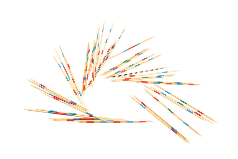 May include: A set of wooden sticks with colored bands, arranged in a circular pattern. The sticks are used for the game pick-up sticks.
