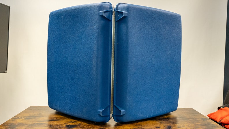 May include: A blue, hard-sided, two-piece suitcase with a silver zipper and clasps.