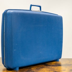 May include: A blue hard-sided suitcase with a handle on top.