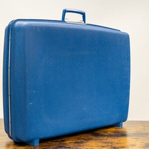 May include: A blue hard-sided suitcase with a handle on top.