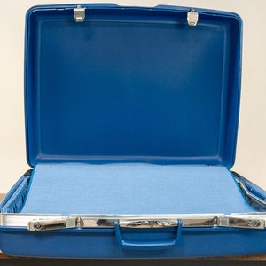 May include: An open blue suitcase with a light blue lining. The suitcase has a silver handle and two silver latches.
