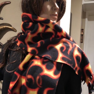 May include: A black and orange fleece scarf with a flame pattern.