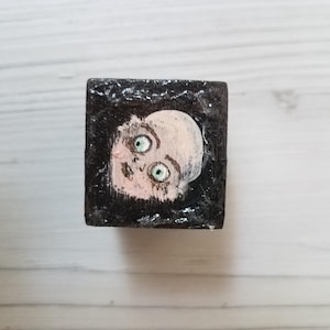 Miniature creepy doll face hand painted on tiny wood block