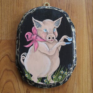 Little piggy holding a cup of tea wearing a big pink bow
