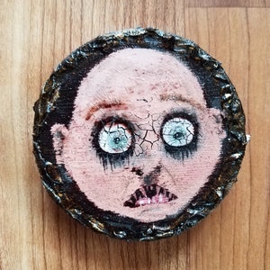 Creepy baby face highly cracked on reclaimed wooden piece with textured edging