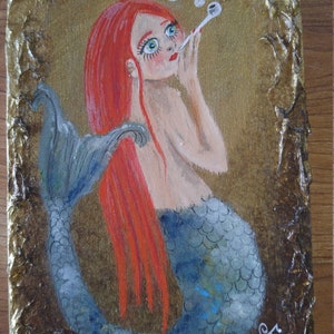 Red haired mermaid blowing bubbles. Hand painted on gold wood with textured edges