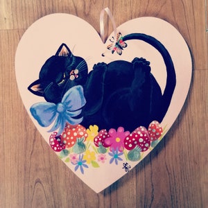 Large pink wooden heart hand painted with a sleeping black cat amongst the toadstools and flowers