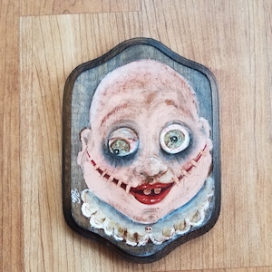 Licking Knives&quot; creepy baby doll head hand painted on decorative wood piece