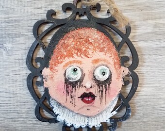 Cara de bebé espeluznante en una pequeña pieza de madera decorativa