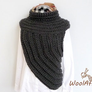 Puede incluir: Un cuello de punto de ganchillo gris con cuello alto. El cuello está drapeado sobre una camisa blanca y se ha estilizado con una bufanda a cuadros.