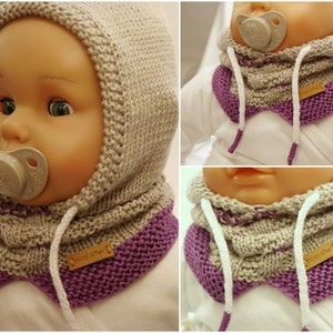 Könnte beinhalten: Ein gestricktes Baby-Mützen- und Schals-Set in Beige und Lila mit weißen Kordeln. Die Mütze hat eine spitze Spitze und der Schal ist ein Schlauchschal. Das Set hat ein Etikett mit der Aufschrift "Wool Affair".