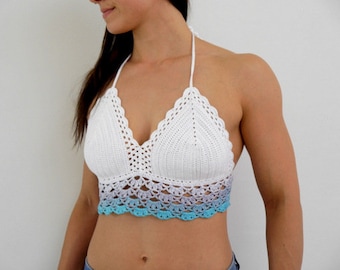 May include: A white crochet halter top with a scalloped edge and a gradient of colors. The top transitions from white to light purple and then to a turquoise blue at the bottom. The top is handmade.