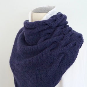 Puede incluir: Una bufanda de cuello de tortuga de punto de color morado oscuro con un patrón de trenza.