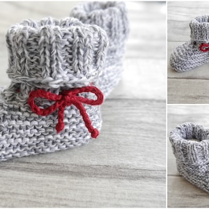 Könnte beinhalten: Graue gestrickte Babyschuhe mit roten Schleifenbändern. Die Schuhe haben ein strukturiertes Strickmuster und sind oben umgeklappt.
