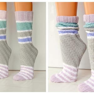 Könnte beinhalten: Ein Paar graue Stricksocken mit rosa, weißen und blauen Streifen. Die Socken sind umgeklappt, um die Streifen zu zeigen.