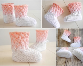 Op de afbeelding: Een paar gebreide babyschoentjes met een roze en witte ombre-design. De schoentjes hebben een kabelbreiselpatroon aan de bovenkant en een glad breisel aan de onderkant.