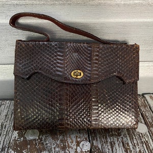 May include: A brown snakeskin handbag with a gold clasp. The bag has a flap closure and a top handle.