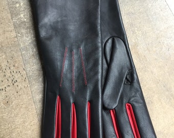 May include: A pair of long black leather gloves with red leather trim on the fingers and cuffs.