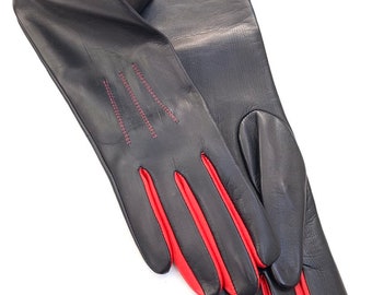 May include: A pair of long black leather gloves with red stitching and red trim on the fingers.