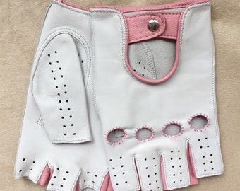 May include: White leather driving gloves with pink stitching and a pink leather accent on the back of the hand. The gloves have fingerless design and a perforated pattern.