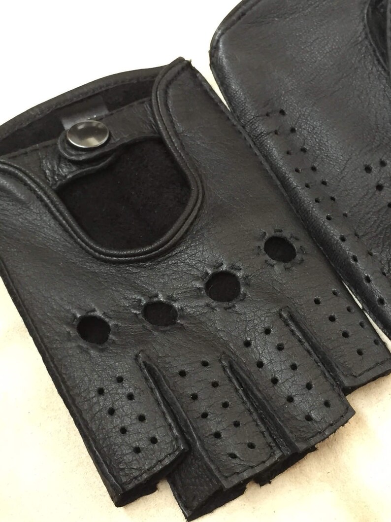 May include: A pair of black leather fingerless gloves with a button closure and a perforated design.
