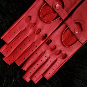 Peut inclure: Une paire de gants de conduite en cuir rouge avec des trous au bout des doigts et une fermeture &agrave; boucle.