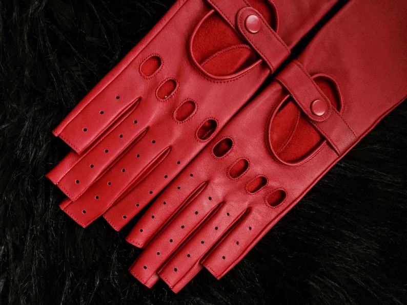Peut inclure: Une paire de gants de conduite en cuir rouge avec des trous au bout des doigts et une fermeture &agrave; boucle.