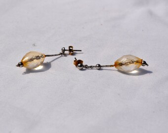 May include: A pair of earrings with clear, teardrop-shaped stones and silver metal accents.