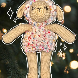 May include: A crocheted stuffed sheep toy with a white base and colorful speckles. The sheep has a closed-eye expression and a small, black nose.